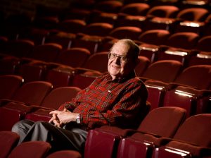 Photo of a man sitting in a red auditorium seat